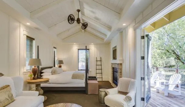 Illustrative property imagery: a bright premium suite interior with a vaulted white ceiling, fireplace and doors opening onto a deck