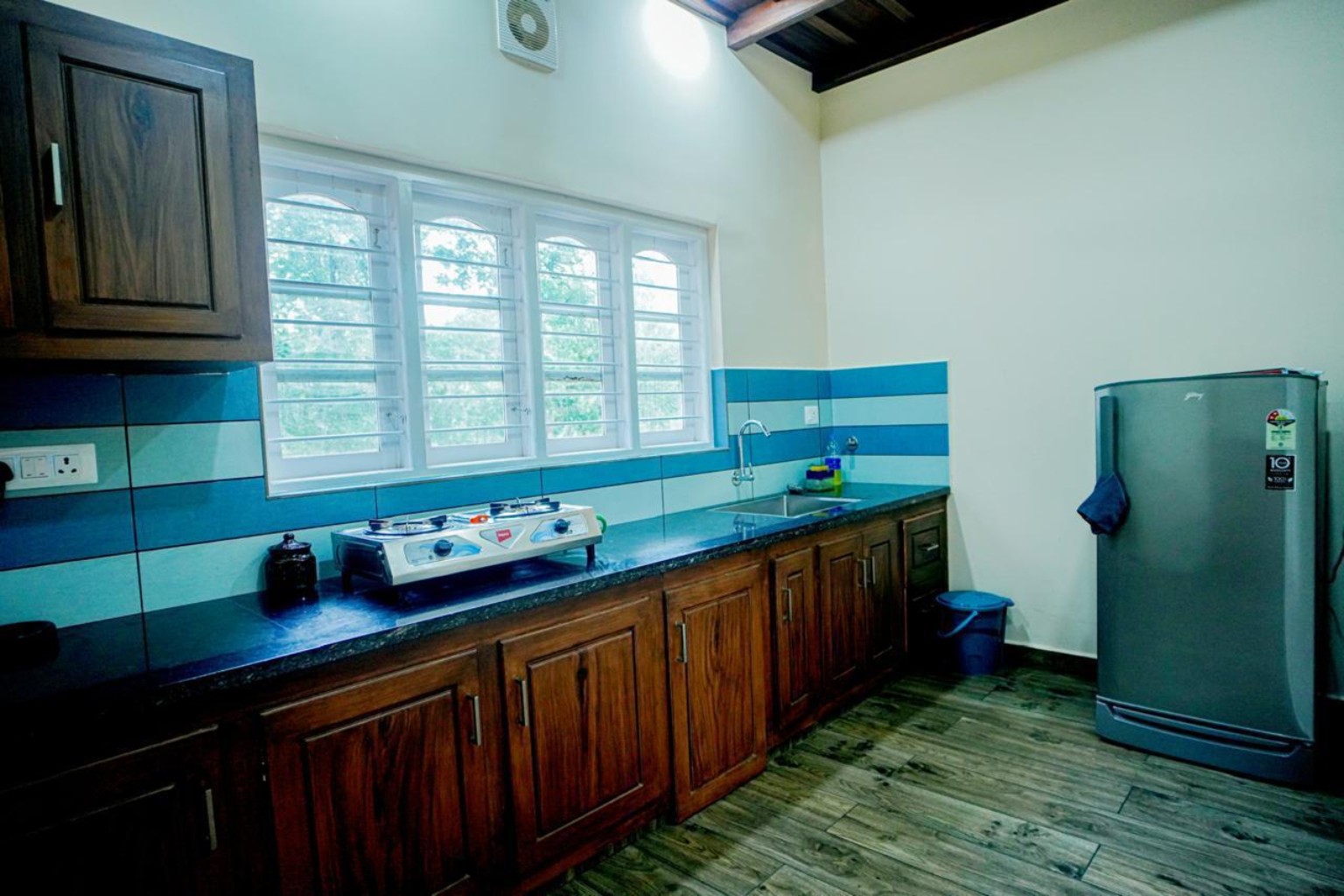 Cottage kitchen with hardwood cabinetry, granite counter, gas hob, sink and refrigerator