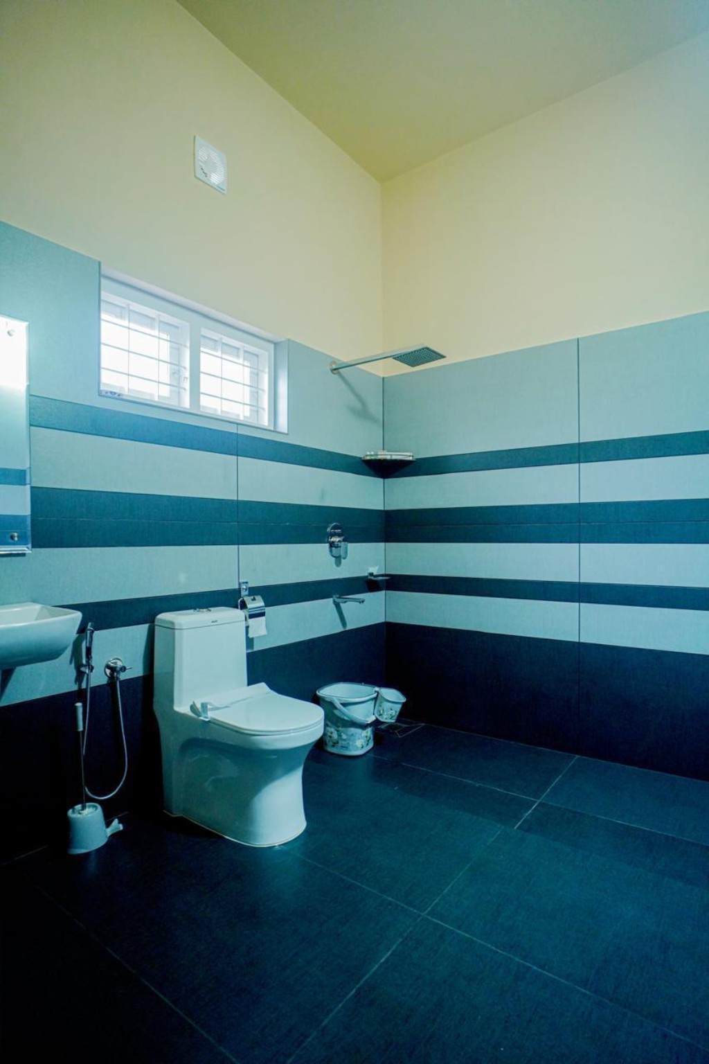Large tiled cottage bathroom in blue and white with rain shower, washbasin and WC