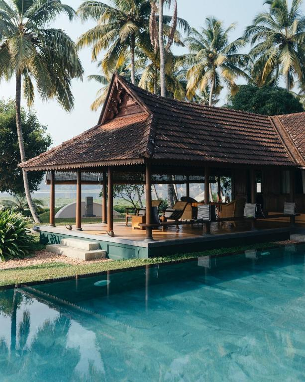 Illustrative destination imagery: an open timber pavilion with a tiled roof beside a still turquoise pool, framed by coconut palms