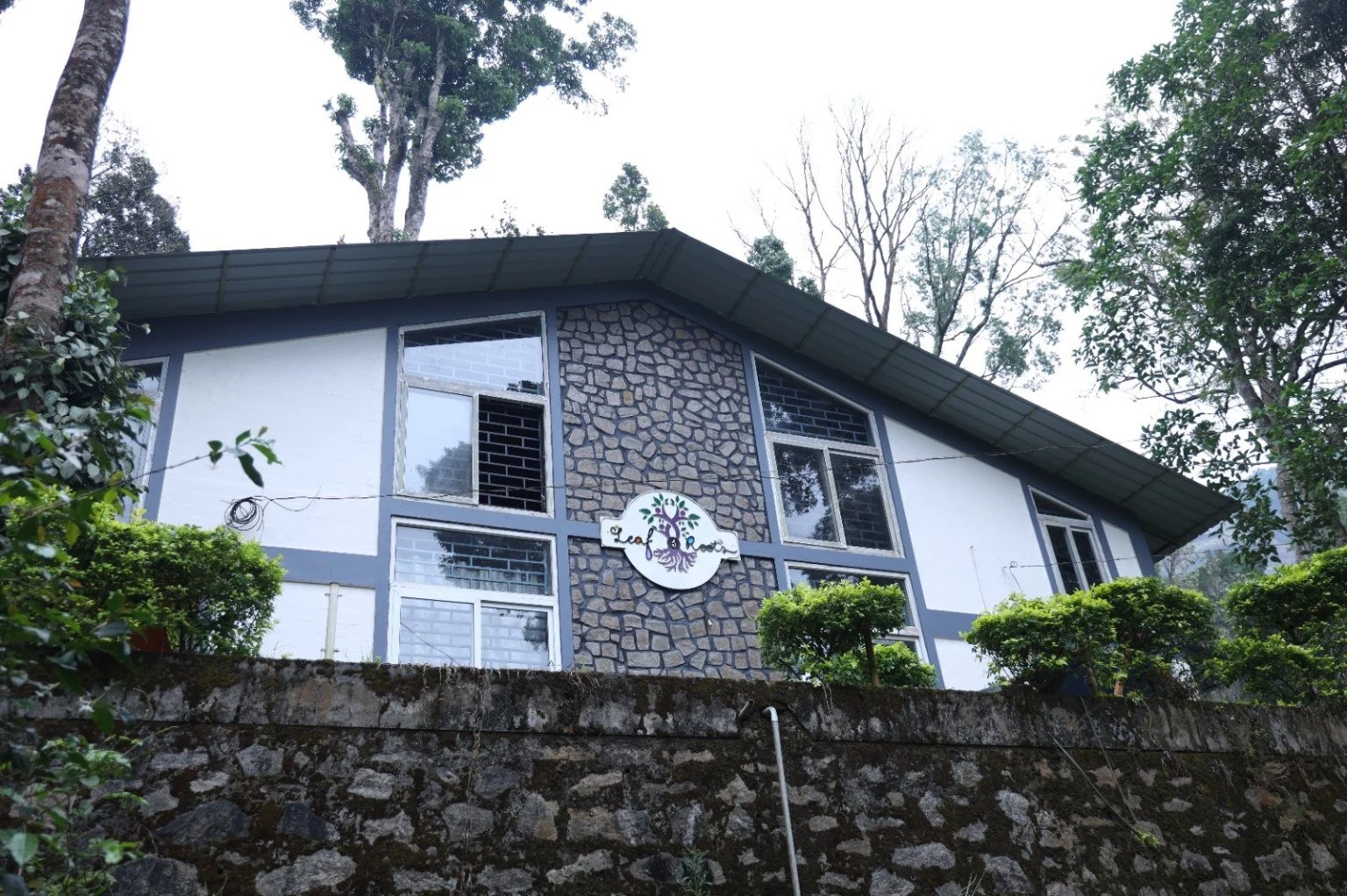 Angled cottage facade with stone cladding above a low stone boundary wall