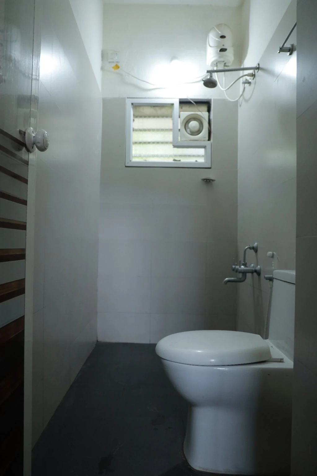 Upright view of the common tiled bathroom with toilet and wall fittings