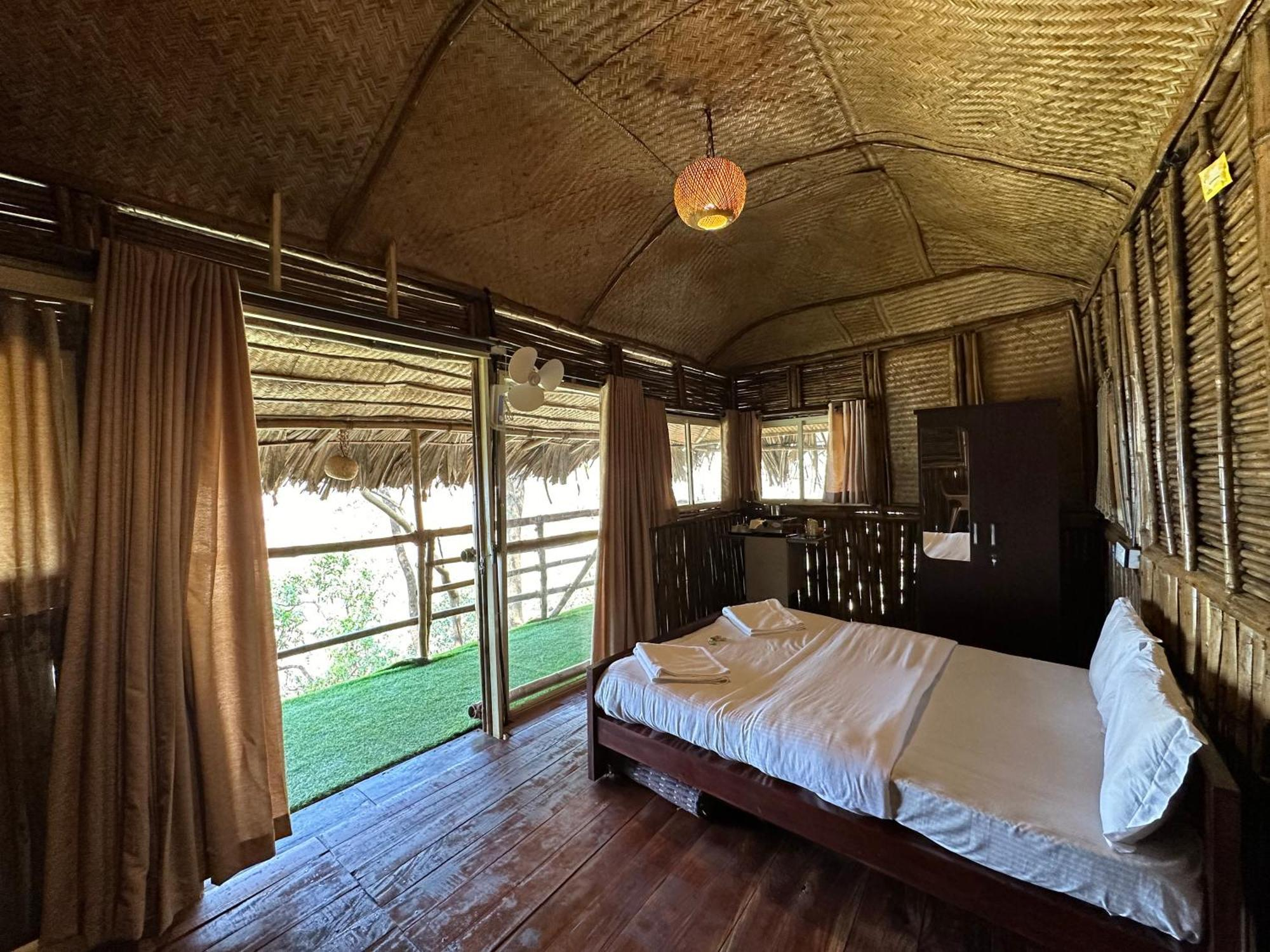 Illustrative property imagery: a calm natural-material cabin bedroom with soft daylight and simple timber furnishings