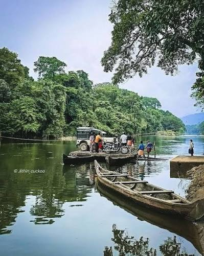 A local crossing the Pooyamkutty river on a narrow raft with bundles aboard