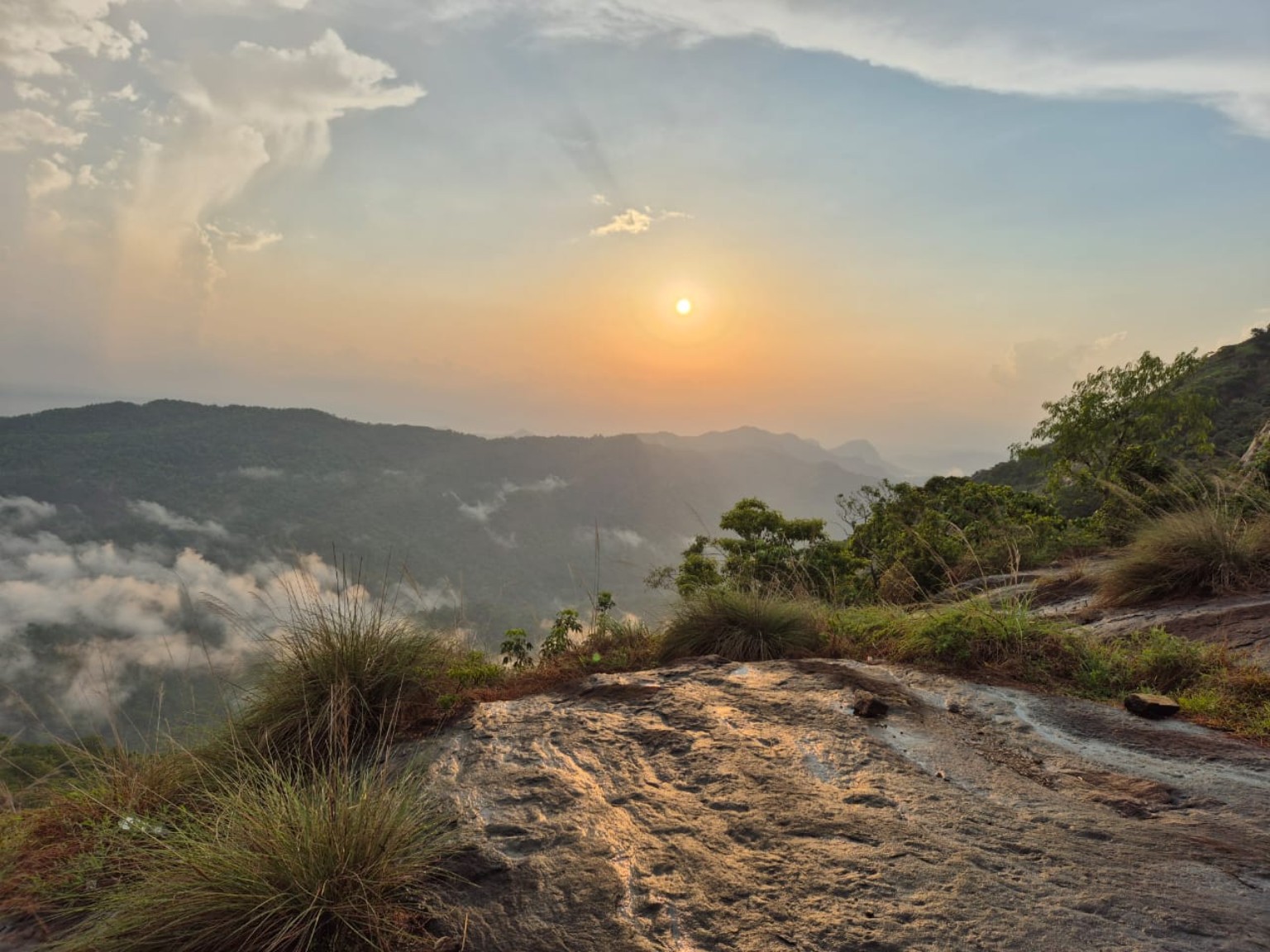 Sunrise from a rock viewpoint above Kuttampuzha with cloud pooling in the forested valleys below