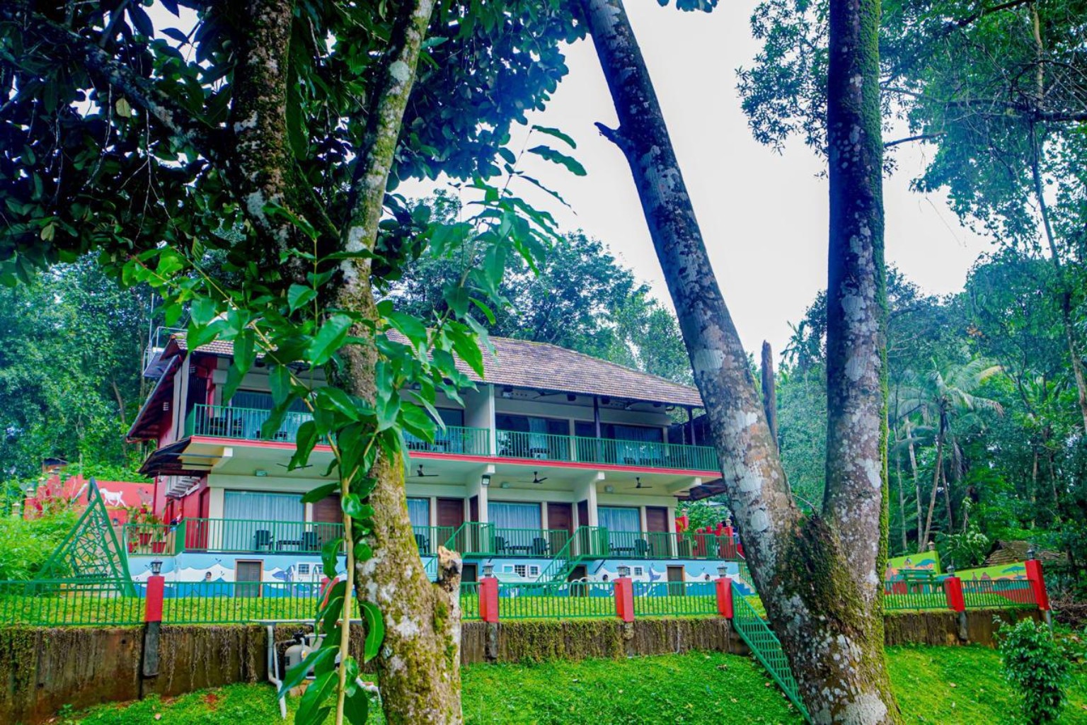 The two-storey Falcon Riverview building with tiled roof, green balconies and lawn beneath tall trees