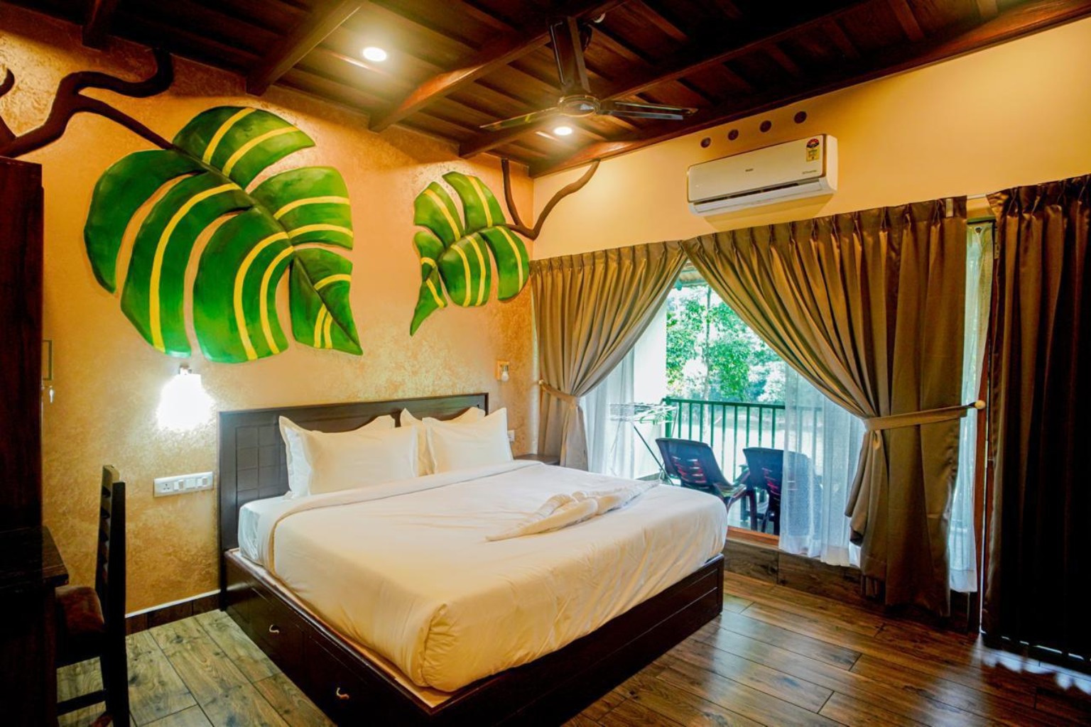 Family room with painted monstera leaves on an ochre wall and a glazed door onto a private balcony