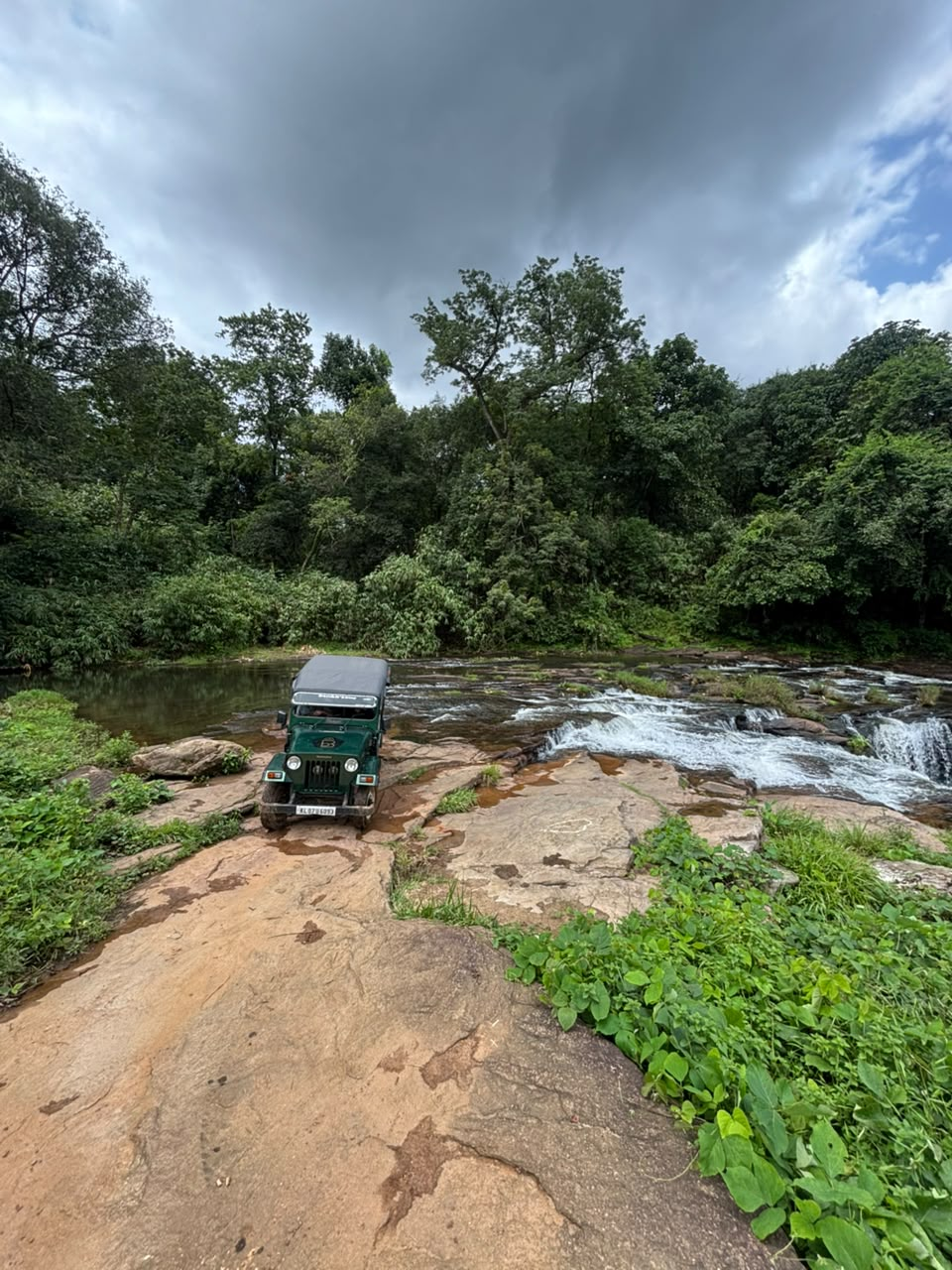 A river cascading over flat rock in the forest near Pooyamkutty